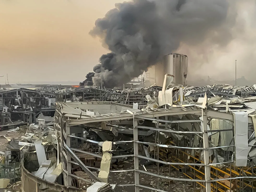 Destroyed city buildings in foreground with black smoke in background