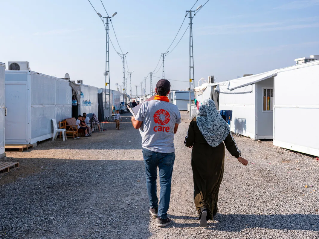 Two people walking together and one person is wearing a Care shirt.