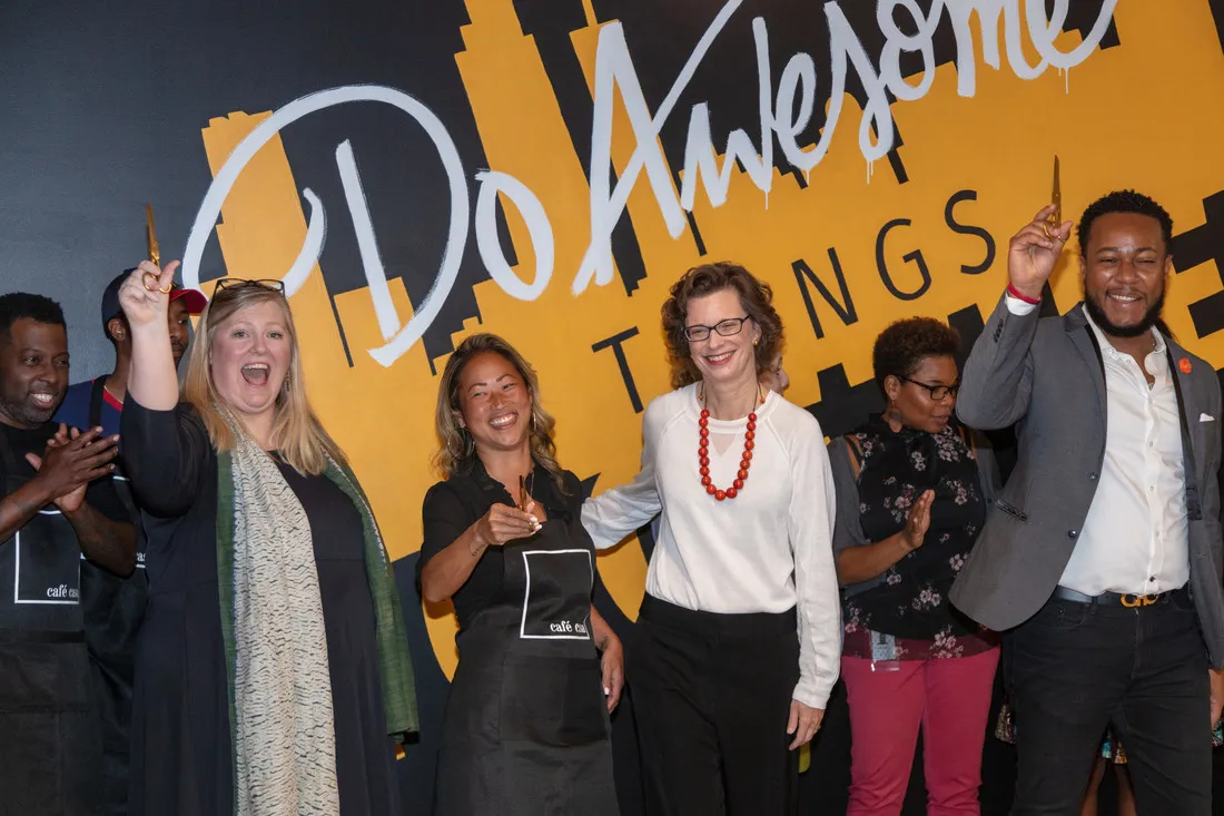 CARE staff members celebrate in front of a mural that says,