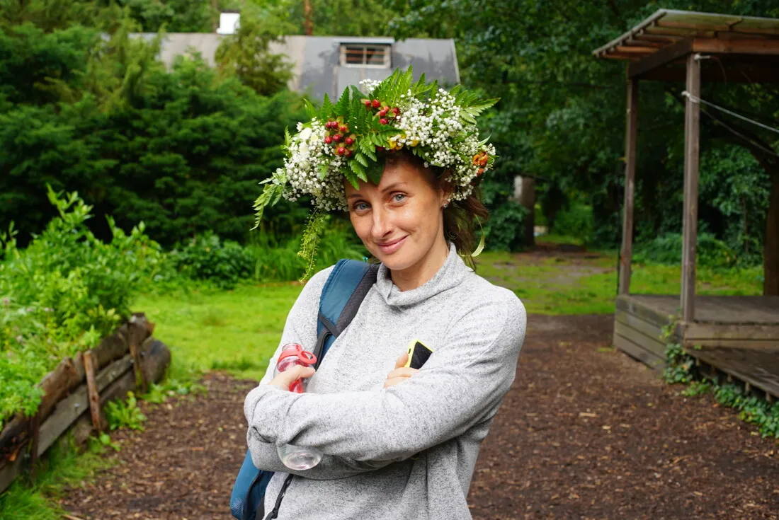 A Polish woman wearing a large flower crown smiles.